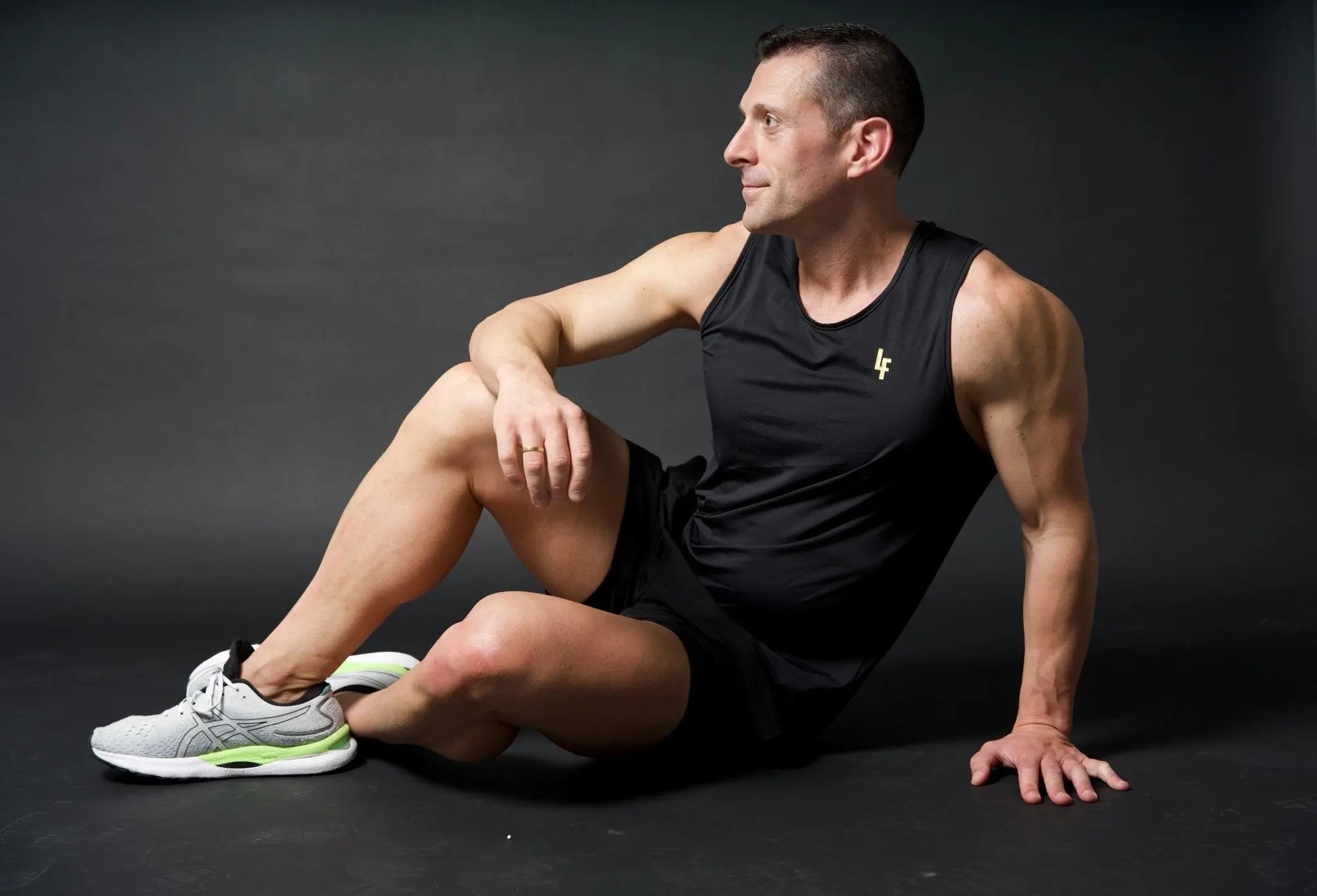 Modelo sentado en pose artística con camiseta técnica sin mangas MAN-U de LUXFEEL en color Negro, diseñada para un alto rendimiento.