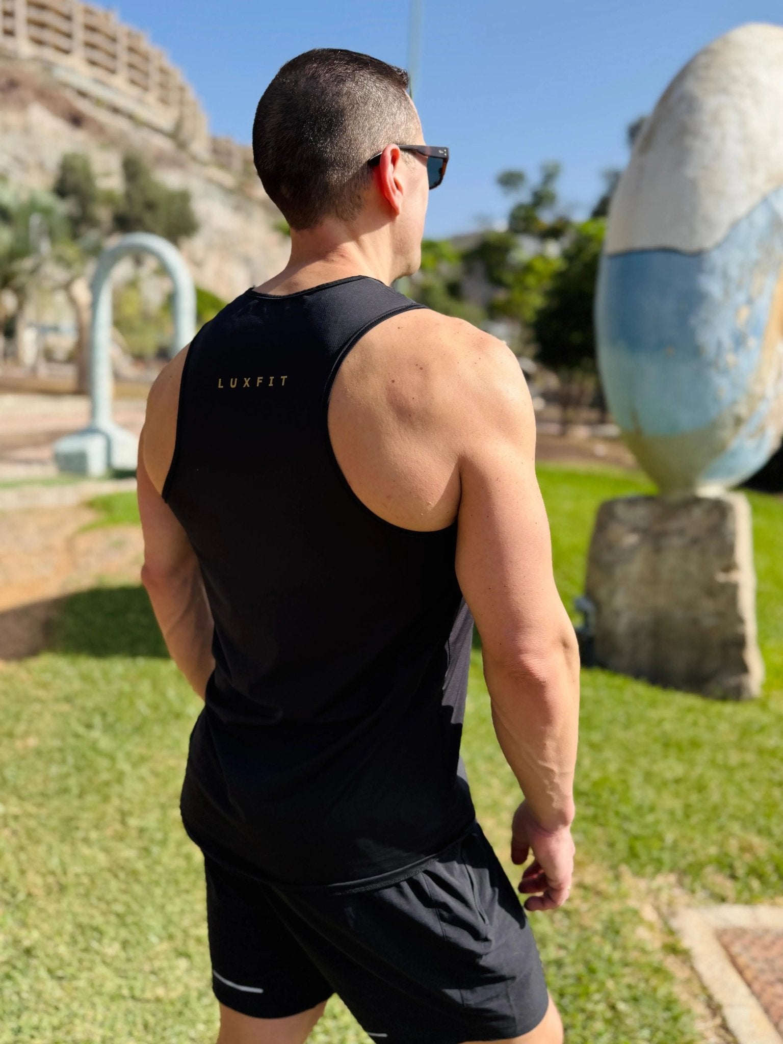 Modelo en el exterior vistiendo la camiseta técnica sin mangas MAN-U de LUXFEEL en color Negro, diseñada para un alto rendimiento.