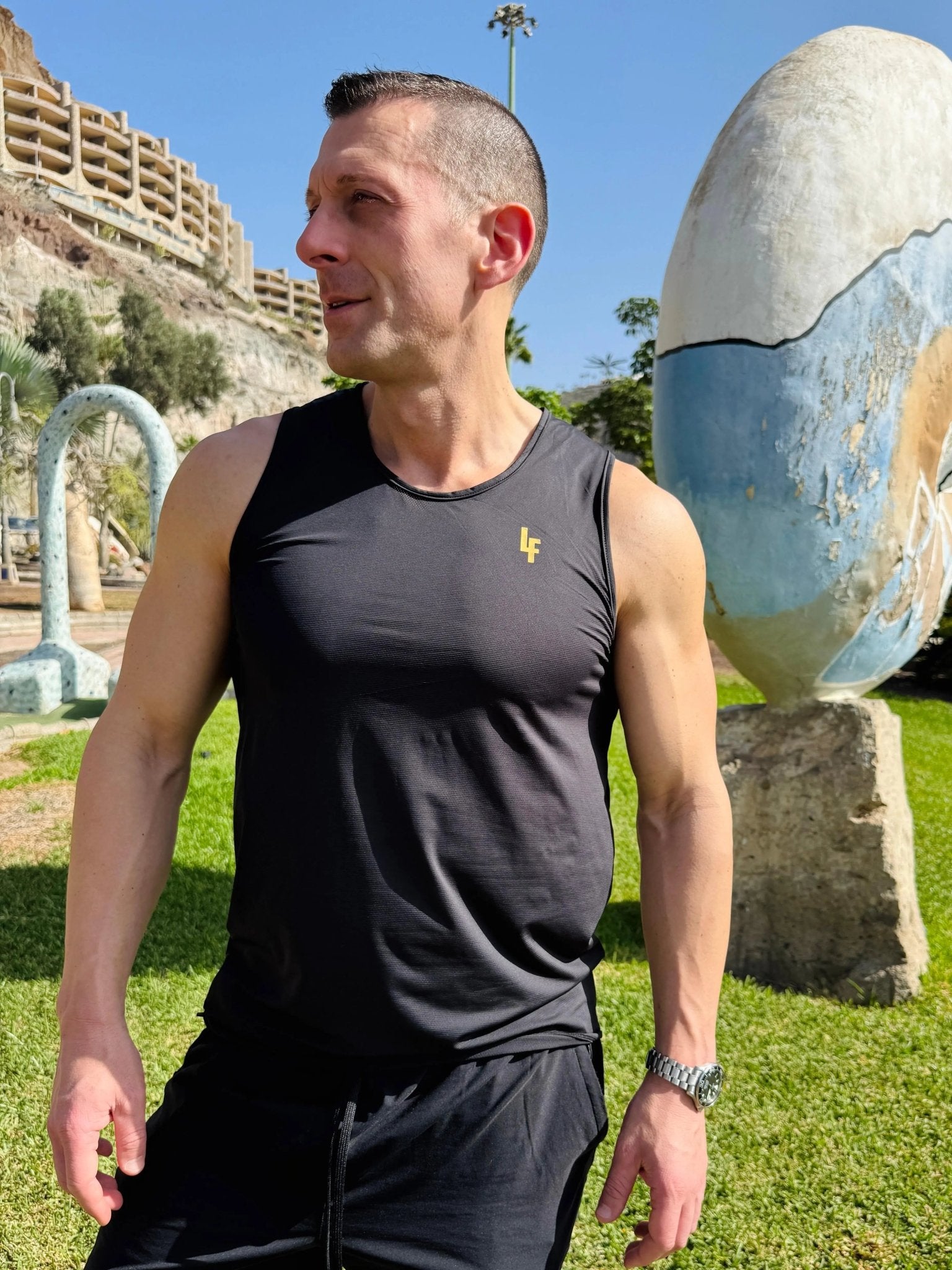 Modelo en el exterior vistiendo la camiseta técnica sin mangas MAN-U de LUXFEEL en color Negro, diseñada para un alto rendimiento.