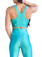 Mujer vistiendo el conjunto deportivo azul celeste de LUXFEEL, compuesto por el crop top brillante Adela Pearl Shine y el legging escultor Myself.