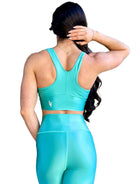 Mujer vistiendo el conjunto deportivo azul celeste de LUXFEEL, compuesto por el crop top brillante Adela Pearl Shine y el legging escultor Myself.