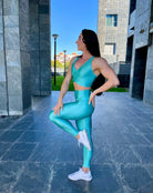 Mujer vistiendo el conjunto deportivo azul celeste de LUXFEEL, compuesto por el crop top brillante Adela Pearl Shine y el legging escultor Myself.
