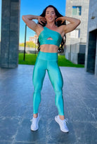 Mujer vistiendo el conjunto azul celeste brillante de LUXFEEL, compuesto por el top asimétrico Carmela (un solo hombro y apertura en el escote) y el legging Pearl Shine a juego.