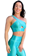 Mujer vistiendo el conjunto azul celeste brillante de LUXFEEL, compuesto por el top asimétrico Carmela (un solo hombro y apertura en el escote) y el legging Pearl Shine a juego.