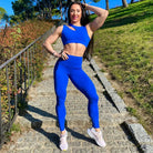 Mujer vistiendo el conjunto deportivo azul de LUXFEEL, compuesto por el top asimétrico Vanesa y el legging escultor Myself.