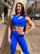 Mujer vistiendo el conjunto deportivo azul de LUXFEEL, compuesto por el top asimétrico Vanesa y el legging escultor Myself.