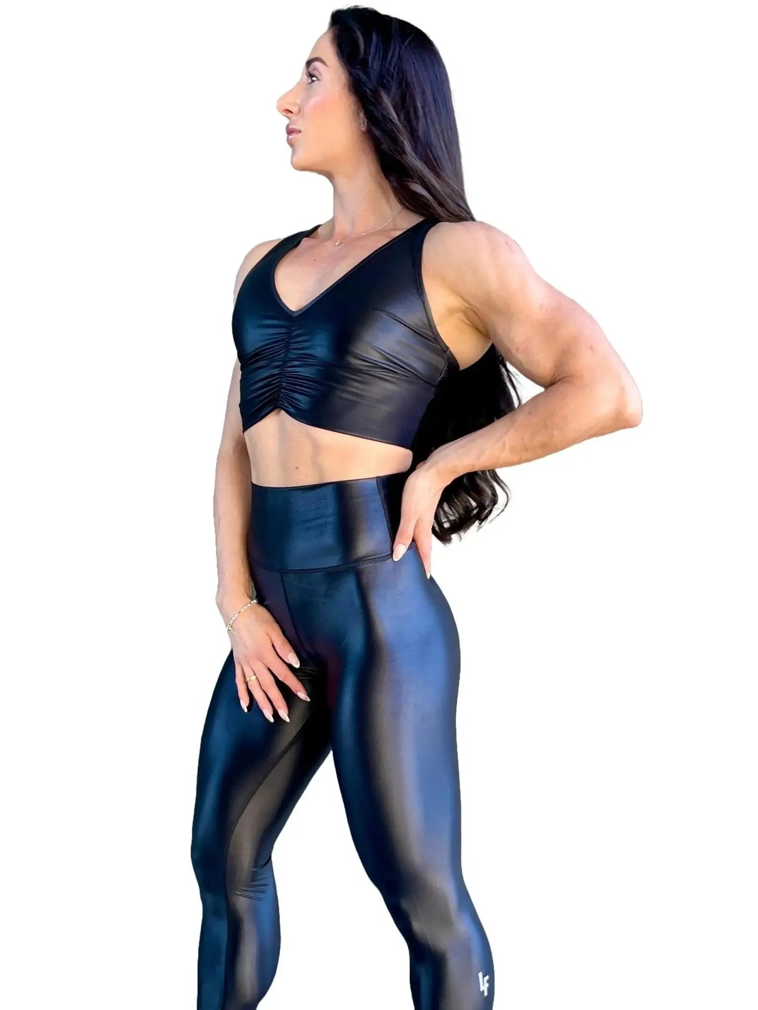 Mujer vistiendo el crop top brillante Top Adela Pearl Shine de LUXFEEL en color Negro Brillante, con escote en V y detalle fruncido en el pecho.