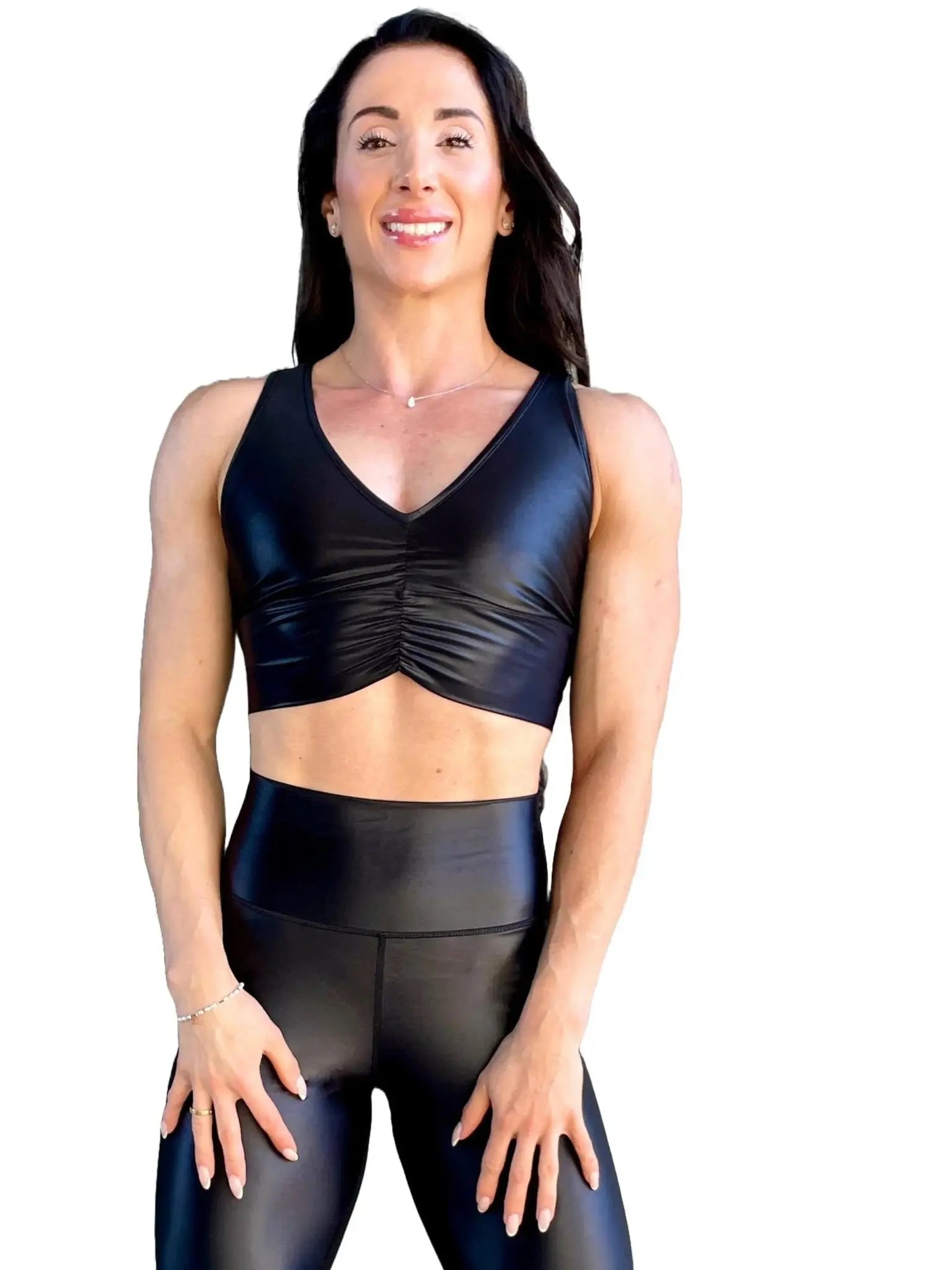 Mujer vistiendo el crop top brillante Top Adela Pearl Shine de LUXFEEL en color Negro Brillante, con escote en V y detalle fruncido en el pecho.