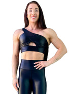 Mujer vistiendo el conjunto deportivo negro brillante de LUXFEEL, compuesto por el top asimétrico Carmela y el legging Pearl Shine