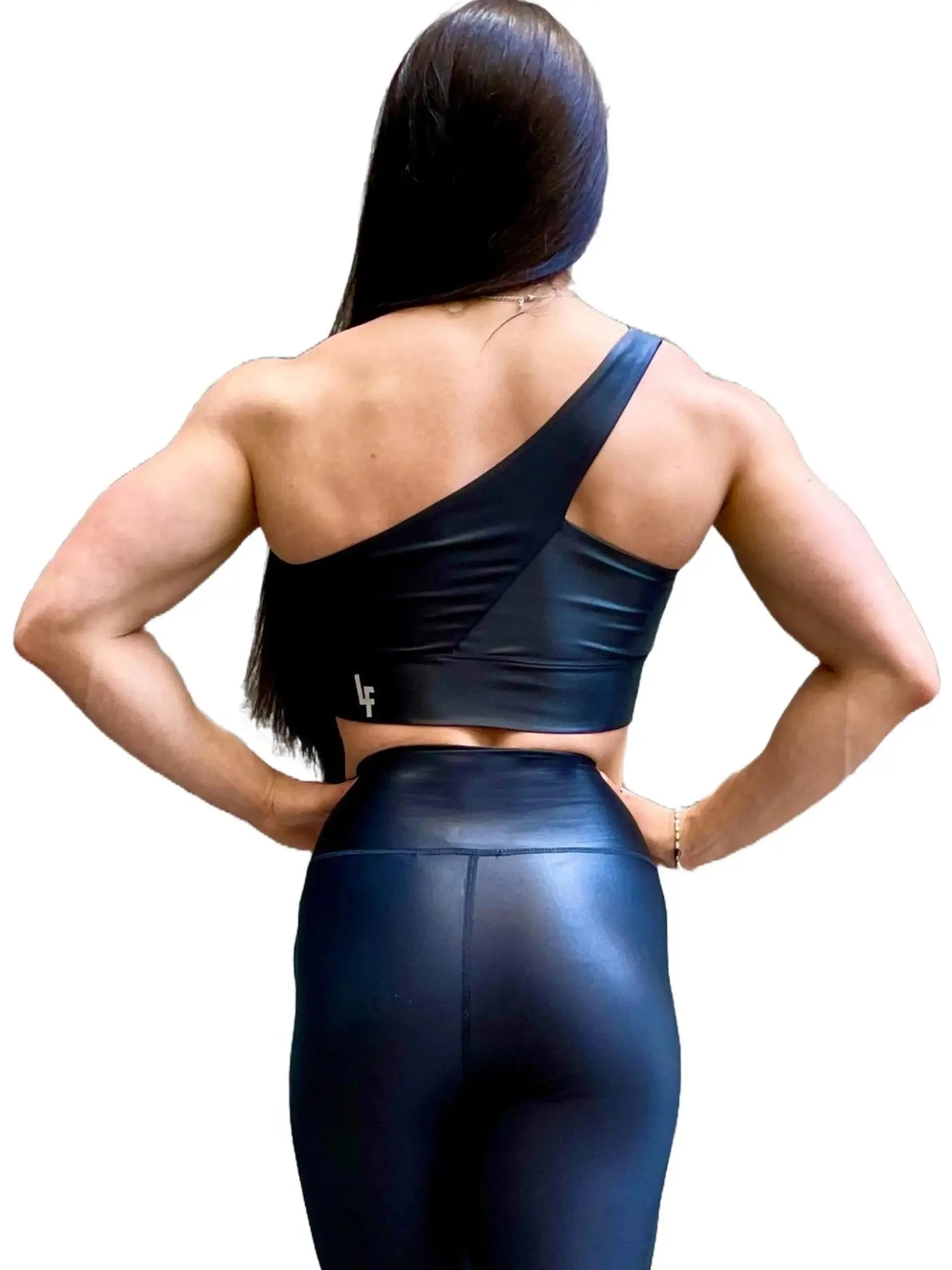 Mujer vistiendo el conjunto deportivo negro brillante de LUXFEEL, compuesto por el top asimétrico Carmela y el legging Pearl Shine