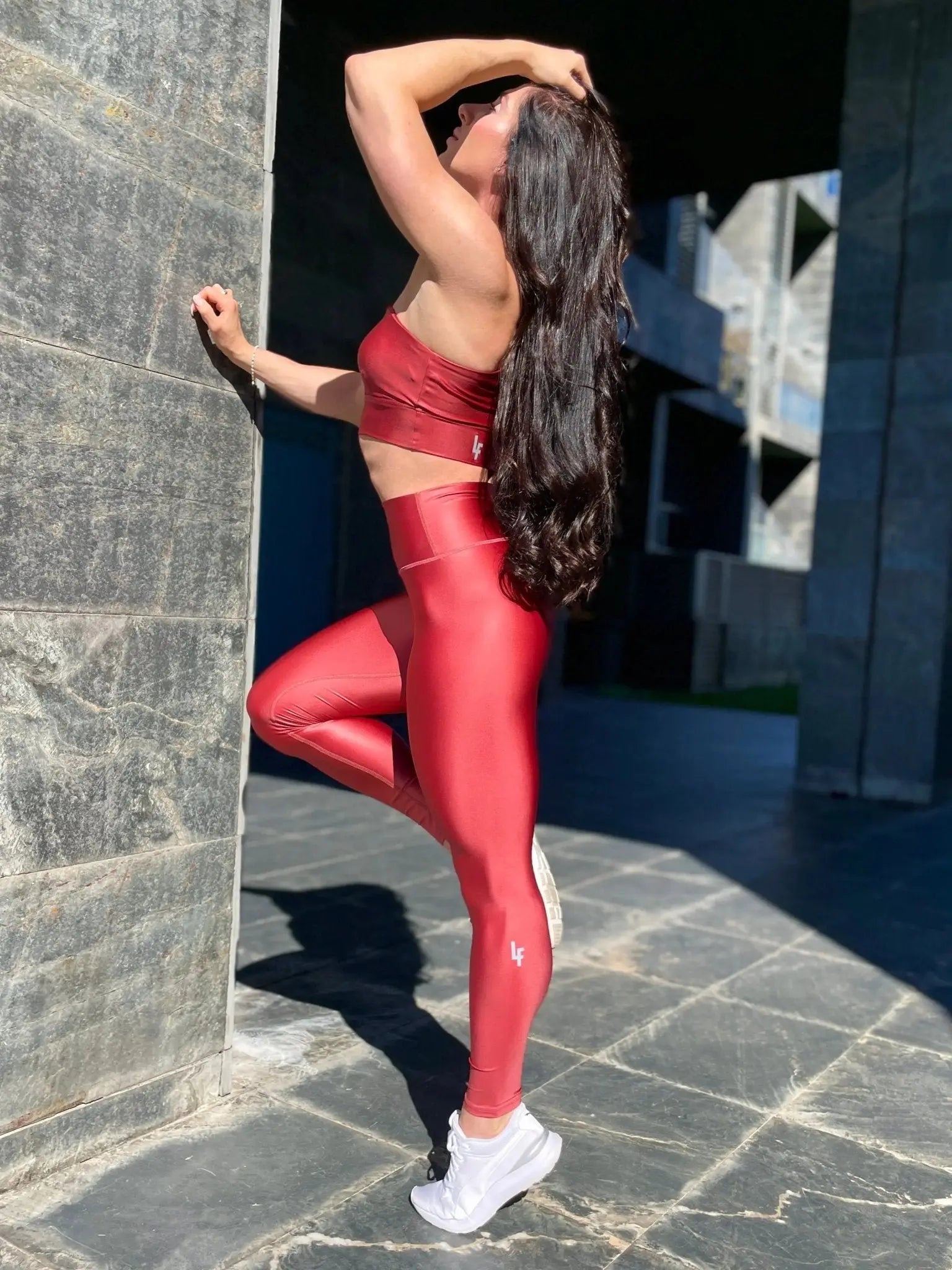 Mujer luciendo el top asimétrico brillante Top Carmela Pearl Shine de LUXFEEL en color Teja Brillante, con diseño de un solo hombro y apertura en el escote.