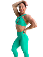Modelo luciendo el conjunto verde de Top Paula y Legging Myself, mostrando el top con su diseño de tirantes cruzados para mayor sujeción.
