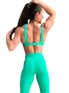 Mujer vistiendo el conjunto deportivo verde de LUXFEEL, con el Top Paula en su estilo de tirantes rectos y el legging escultor Myself.