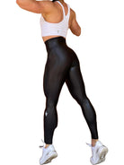 Mujer vistiendo los leggings brillantes de cintura alta Legging Pearl Shine de LUXFEEL en color Negro Brillante, con acabado efecto perla.