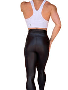 Mujer vistiendo los leggings brillantes de cintura alta Legging Pearl Shine de LUXFEEL en color Negro Brillante, con acabado efecto perla.