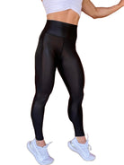 Mujer vistiendo los leggings brillantes de cintura alta Legging Pearl Shine de LUXFEEL en color Negro Brillante, con acabado efecto perla.
