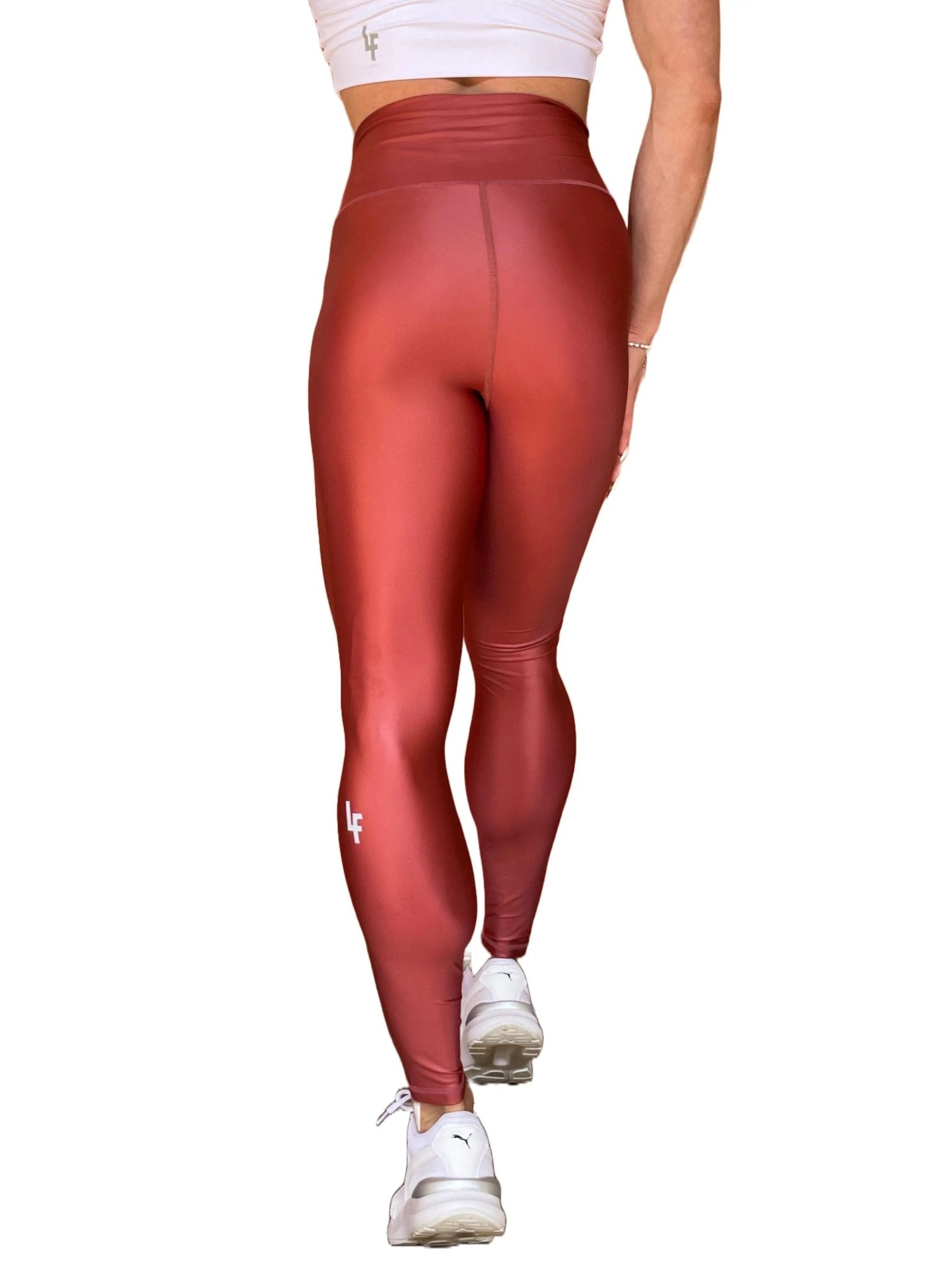 Mujer vistiendo los leggings brillantes de cintura alta Legging Pearl Shine de LUXFEEL en color Teja Brillante / Marron Brillante, con acabado efecto perla.