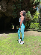 Mujer vistiendo los leggings brillantes de cintura alta Legging Pearl Shine de LUXFEEL en color Azul Celeste Brillante, con acabado efecto perla.