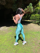 Mujer vistiendo los leggings brillantes de cintura alta Legging Pearl Shine de LUXFEEL en color Azul Celeste Brillante, con acabado efecto perla.