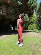 Mujer vistiendo los leggings brillantes de cintura alta Legging Pearl Shine de LUXFEEL en color Teja Brillante / Marron Brillante, con acabado efecto perla.