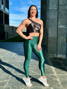 Mujer vistiendo los leggings brillantes de cintura alta Legging Pearl Shine de LUXFEEL en color Verde Botella Brillante, con acabado efecto perla.