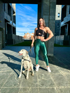 Mujer vistiendo los leggings brillantes de cintura alta Legging Pearl Shine de LUXFEEL en color Verde Botella Brillante, con acabado efecto perla.