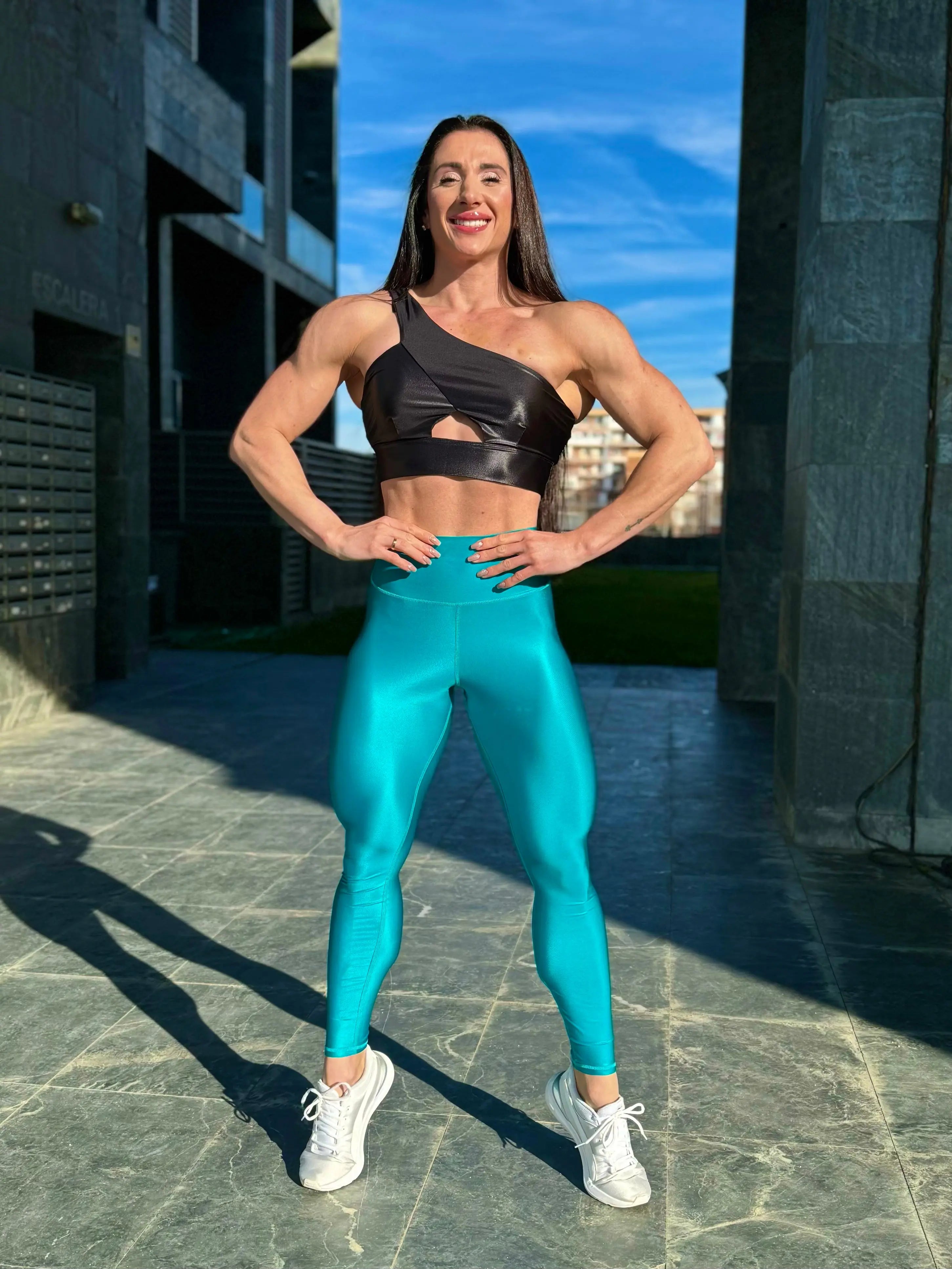 Mujer vistiendo los leggings brillantes de cintura alta Legging Pearl Shine de LUXFEEL en color Azul Capri Brillante, con acabado efecto perla.