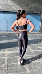 Mujer vistiendo los leggings brillantes de cintura alta Legging Pearl Shine de LUXFEEL en color Negro Brillante, con acabado efecto perla.