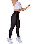 Mujer vistiendo los leggings brillantes de cintura alta Legging Pearl Shine de LUXFEEL en color Negro Brillante, con acabado efecto perla.