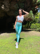 Mujer vistiendo los leggings brillantes de cintura alta Legging Pearl Shine de LUXFEEL en color Azul Celeste Brillante, con acabado efecto perla.
