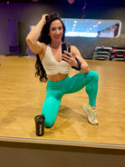 Mujer vistiendo el crop top deportivo Top Adela de LUXFEEL en color Blanco, con escote en V y detalle fruncido en el pecho.