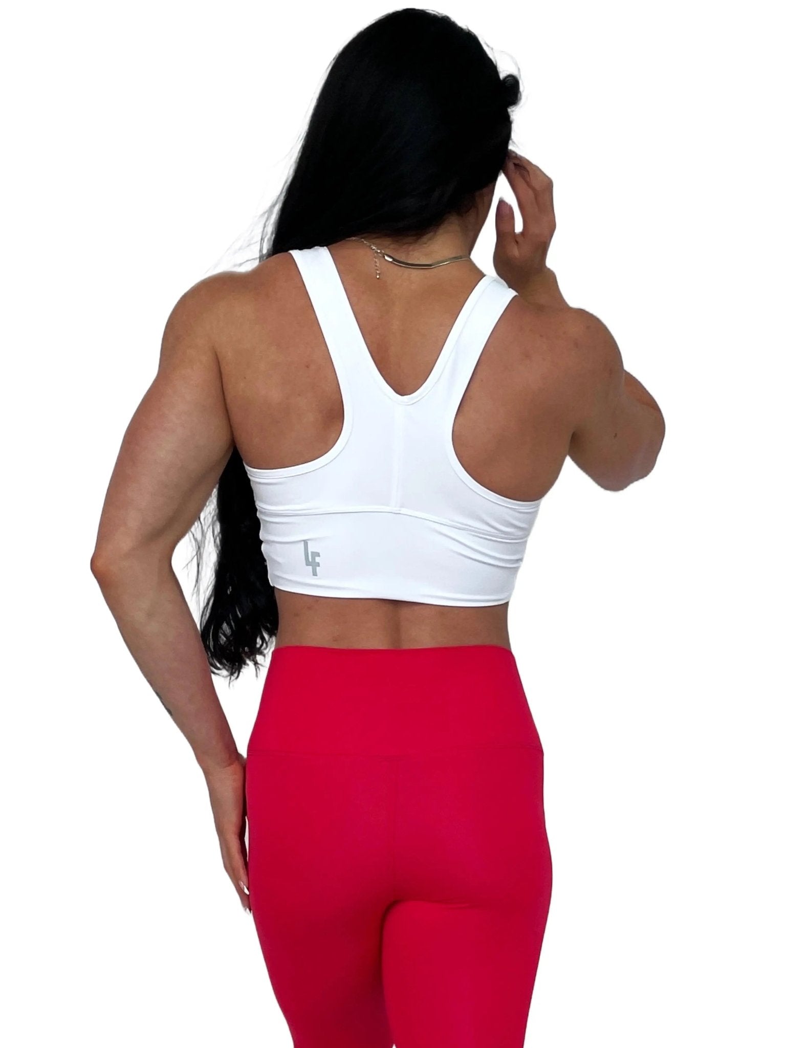 Mujer vistiendo el crop top deportivo Top Adela de LUXFEEL en color Blanco, con escote en V y detalle fruncido en el pecho.