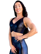 Mujer vistiendo el crop top brillante Top Adela Pearl Shine de LUXFEEL en color Negro Brillante, con escote en V y detalle fruncido en el pecho.