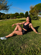 Mujer vistiendo el crop top deportivo Top Adela (tumba en el campo) de LUXFEEL en color Negro, con escote en V y detalle fruncido en el pecho.