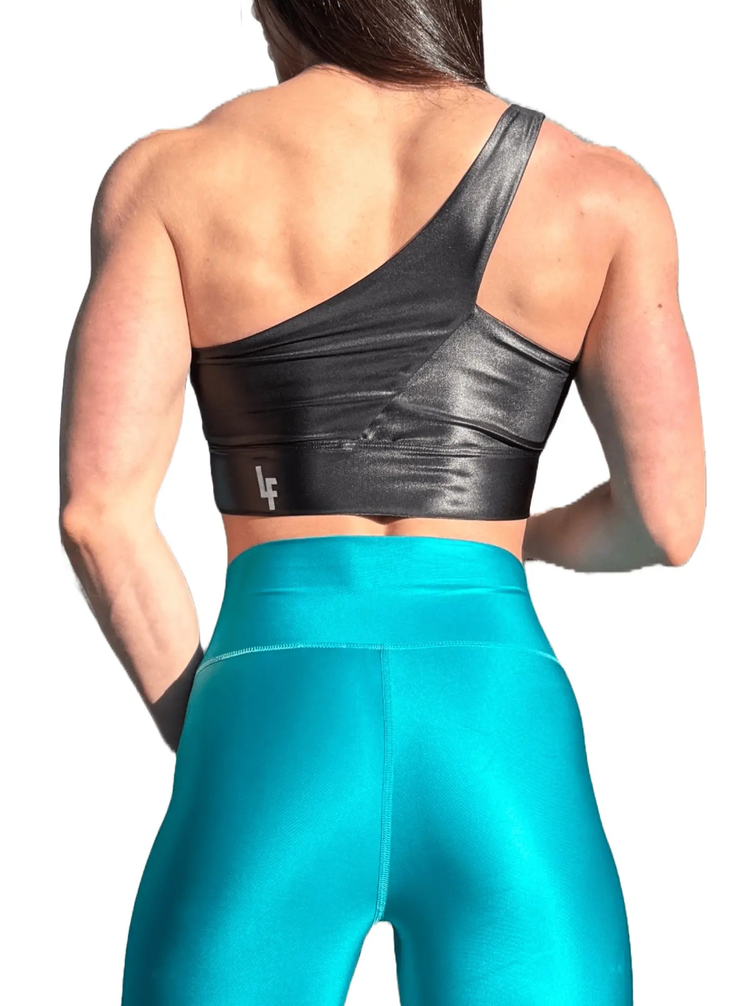 Mujer luciendo el top asimétrico brillante Top Carmela Pearl Shine de LUXFEEL en color Negro Brillante, con diseño de un solo hombro y apertura en el escote.