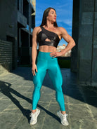 Mujer vistiendo los leggings brillantes de cintura alta Legging Pearl Shine de LUXFEEL en color Azul Capri Brillante, con acabado efecto perla.