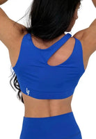 Mujer vistiendo el conjunto deportivo azul de LUXFEEL, compuesto por el top asimétrico Vanesa y el legging escultor Myself.