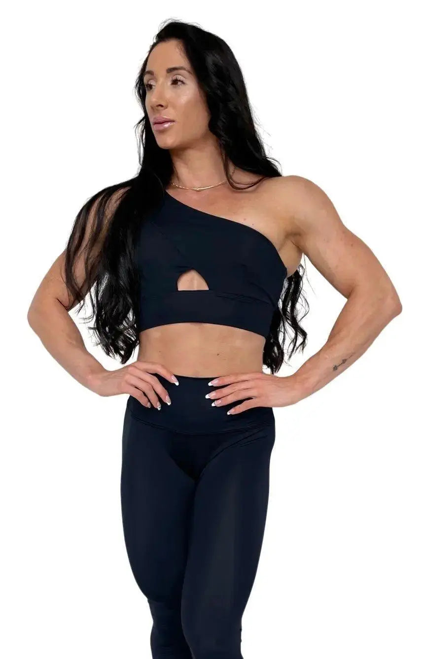 Mujer vistiendo el conjunto deportivo negro de LUXFEEL, compuesto por el top asimétrico Carmela y el legging escultor Myself.