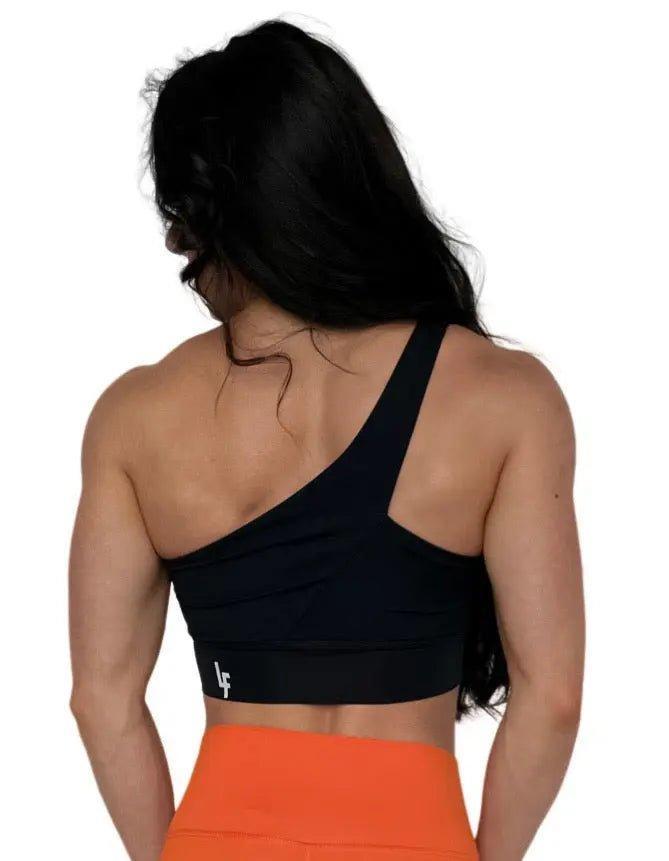 Mujer luciendo el top asimétrico Top Carmela de LUXFEEL en color Negro, con diseño de un solo hombro y apertura en el escote