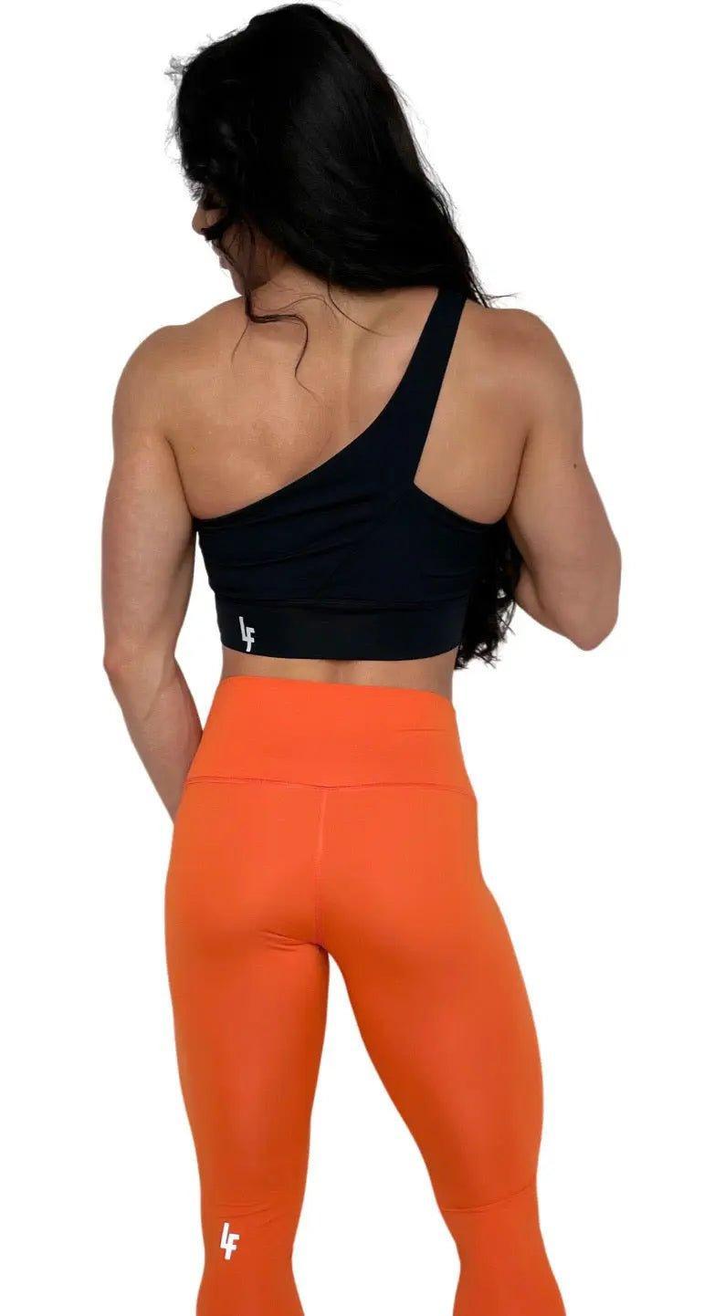 Mujer luciendo el top asimétrico Top Carmela de LUXFEEL en color Negro, con diseño de un solo hombro y apertura en el escote