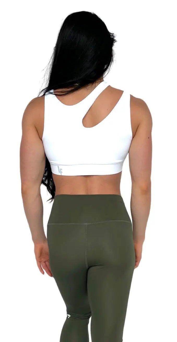 Mujer luciendo el top asimétrico Top Vanesa de LUXFEEL en color Blanco, con un diseño de apertura en el hombro y soporte extra.